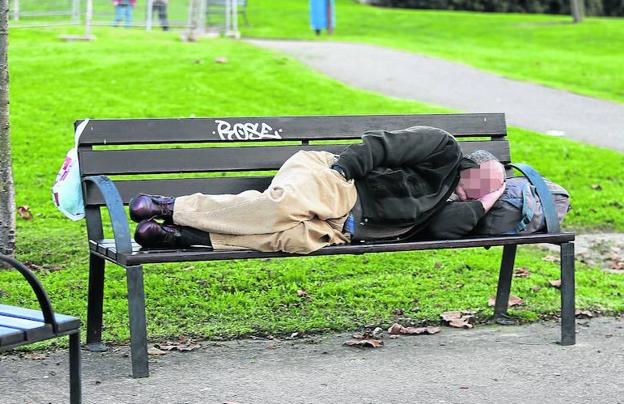 Una persona sin recursos duerme en el banco de un parque de Gijón.