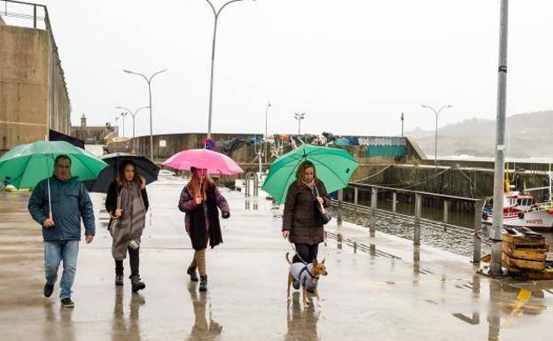 Turistas paseando bajo la lluvia en Llanes./JUAN GARCÍA LLACA
