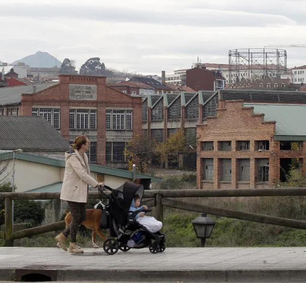 Un mujer paseo a un bebé y un perro delante de La Vega. / M. ROJAS