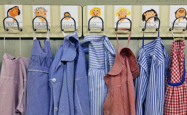 Los babis de los alumnos de un centro escolar de Barcelona, colgados en sus perchas. /Alberto Estévez (Efe)