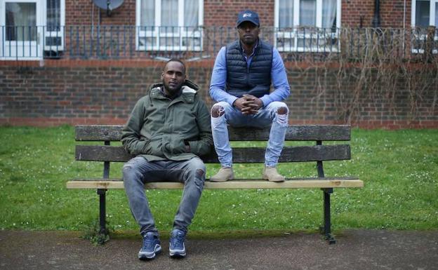 Anthon Dinnall (i) y Abdi, antiguos delincuentes, posan en un banco de su barrio. /Daniel LEAL-OLIVAS (AFP)