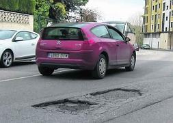 Un coche esquiva los baches que hay a la salida de Piedras Blancas. :: S. L./
