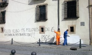 Dos operarios municipales limpian una pintada de la fachada del Consistorio de Cangas. :: AZCÁRATE/