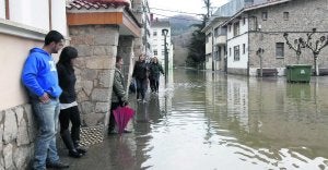 Los vecinos del barrio de El Barco, en Arriondas, contemplando el pasado febrero la calle anegada como consecuencia de la crecida que tuvo el Sella aquel mes. :: NEL ACEBAL/