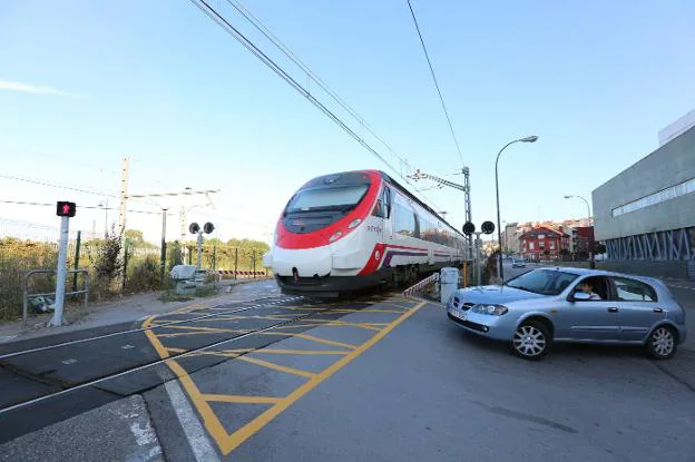 Un tren de cercanías que cubre la línea entre Avilés y Oviedo, a su paso por el paso a nivel de la calle de El Muelle. / MARIETA