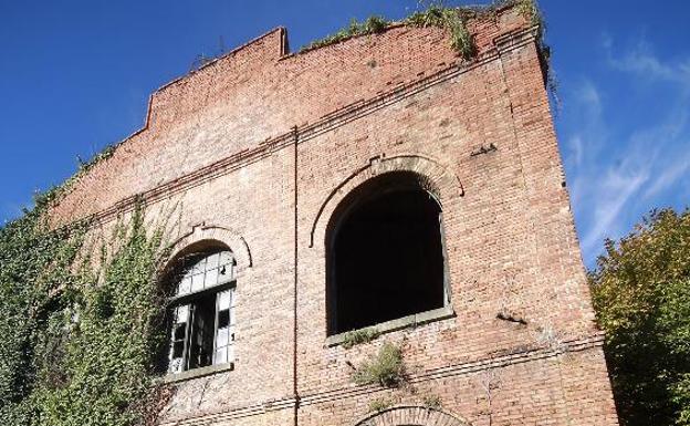 Una mujer frente a una nave de la antigua fábrica de La Vega./