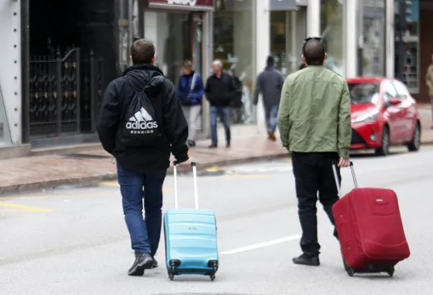 Asturianos con sus maletas en Oviedo tras un viaje. / PABLO LORENZANA