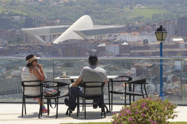 Dos socios disfrutan de la terraza del Centro Asturiano, con vistas a Oviedo. / MARIO ROJAS