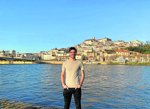 El gijonés Alejandro Caballero a la orilla del río Mondego, con la ciudad de Coimbra a sus espaldas. / E. C.