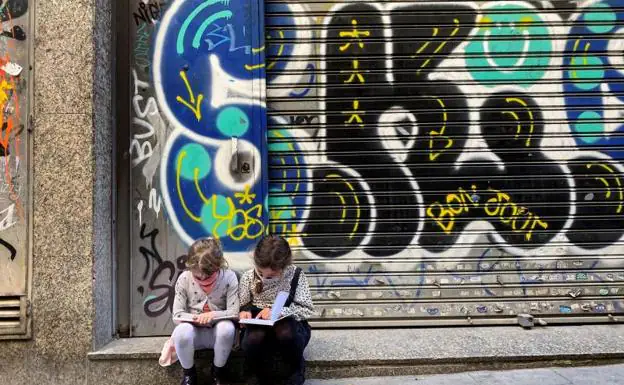 Dos niñas leen sendos libros sentadas en una calle del centro de Barcelona /EFE