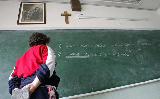 n niño, en un aula de Oviedo, con el crucifijo sobre la pizarra. /MARIO ROJAS