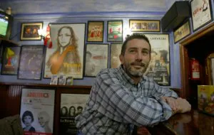 Agustín Gutiérrez, 'Guti', posa delante de la barra con los carteles de obras de teatro dedicados por los actores detrás. ::                             MARIETA/